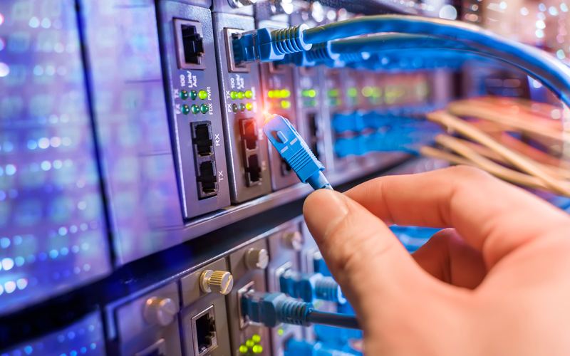 Инженер за работой с оптическим кроссом в серверной